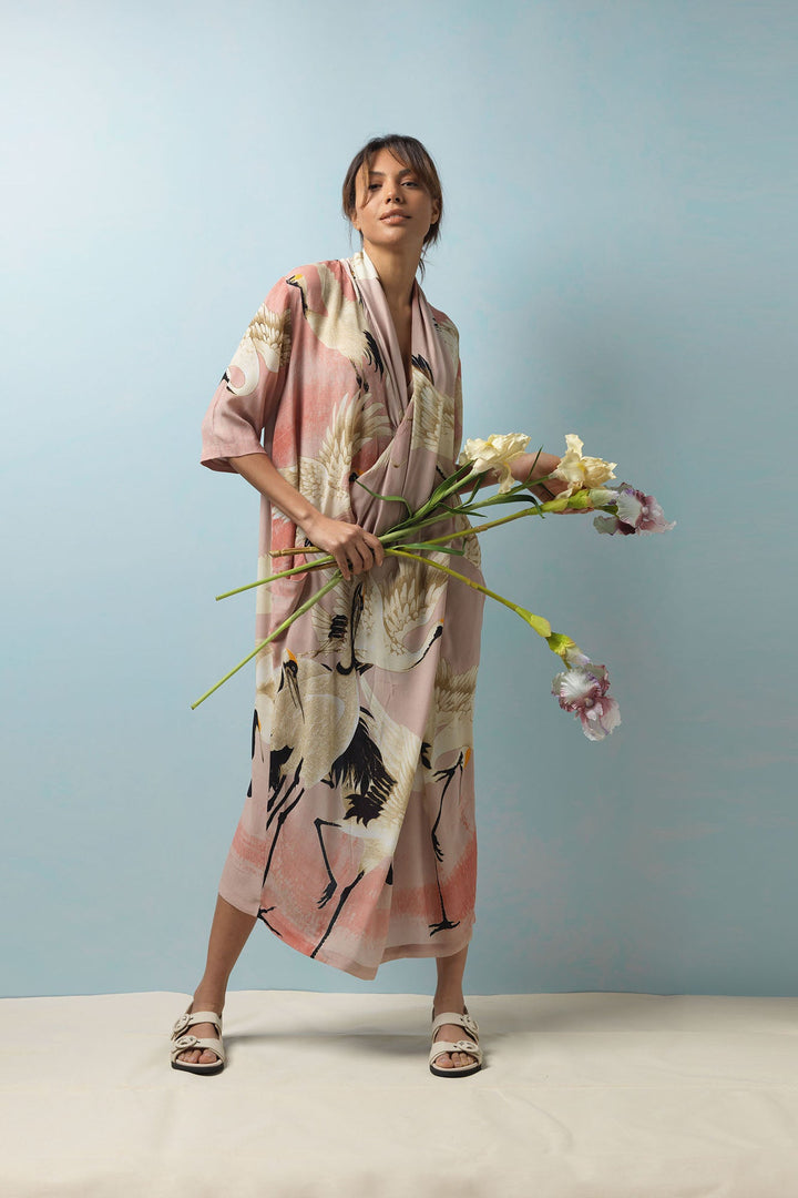Our One Hundred Stars Stork Crane Pink Midi Dress features a flattering vintage inspired cowl neck, V line dress features a pin tuck front, pockets and can be styled with your own additional belt to create a silhouette look. The print features wonderful art deco cranes and storks on an stylish pastel pink background. 